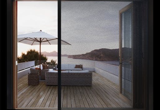 An open Andersen big door with retractable screen facing a deck and oceanside views