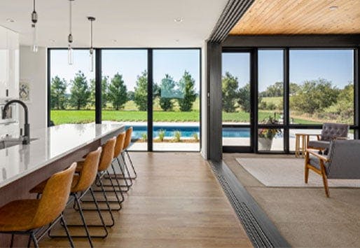A kitchen and porch with floor-to-ceiling windows facing a backyard swimming pool.