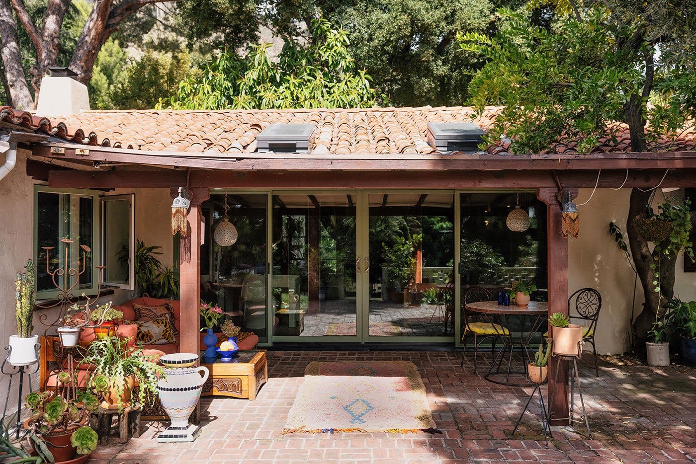 A four-panel sliding patio door connects to a brick-paved courtyard that’s partially shaded by a roof overhang.