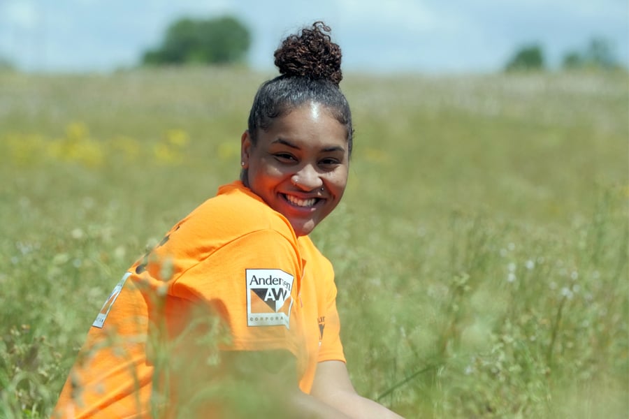 Andersen Employee smiling in a prairie with an Andersen shirt on