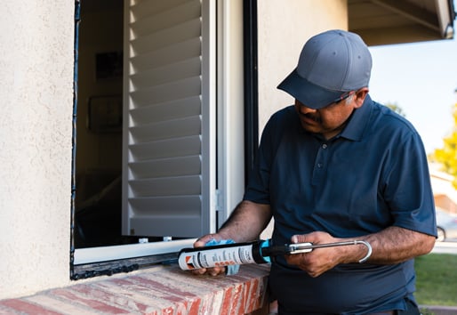 Window installer applying sealer on window