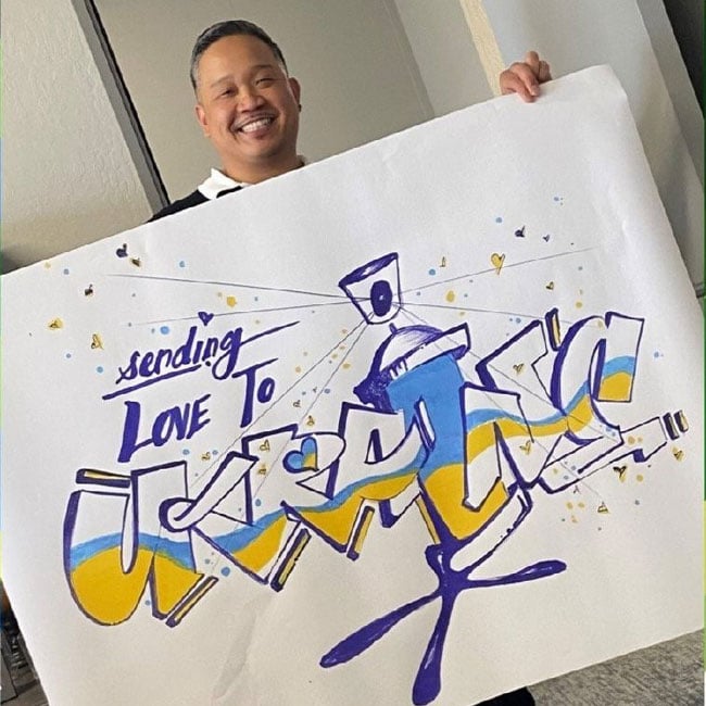 man holding a sign that reads 'sending love to ukraine'