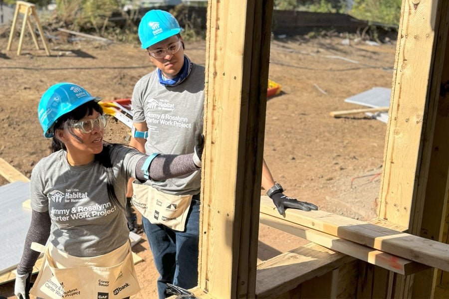 Man and woman standing on job site with hard hats and safety glasses on