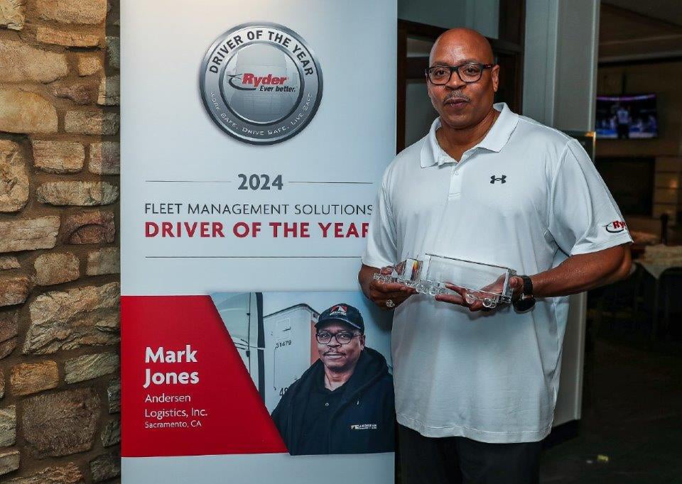 Mark Jones standing by award banner while holding crystal truck award
