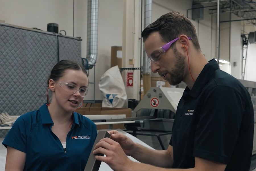 Man and woman discussing window parts with safety glasses and ear plugs