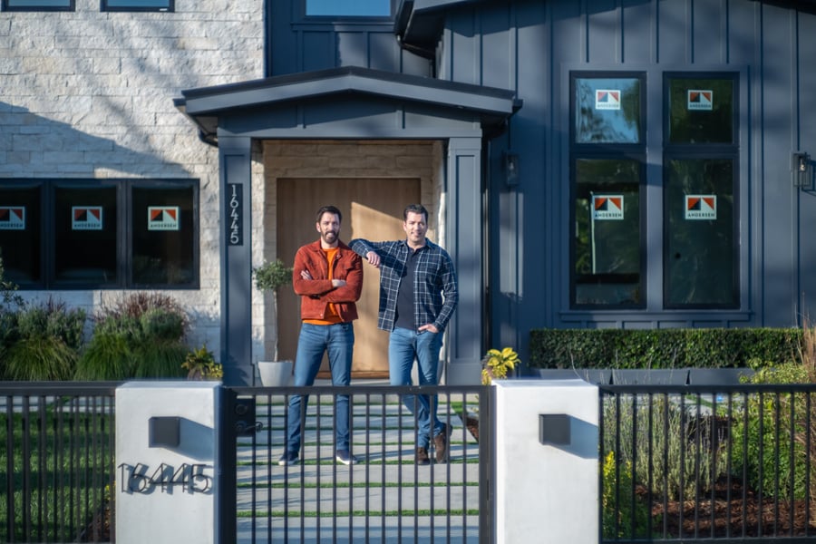 Drew and Jonathan Scott standing in front of new home with Andersen Windows stickers on the windows