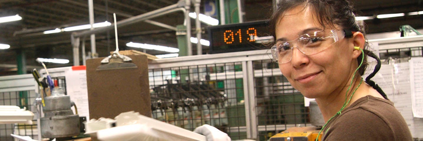 Woman working in manufacturing plant smiling