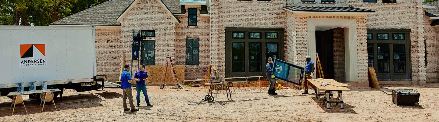 Andersen contractors on site installing windows with an Andersen truck parked nearby