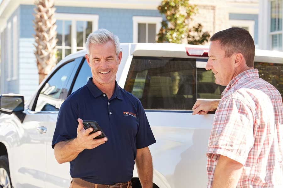 Andersen Certified Contractor smiling while showing phone to homeowner outside a home.