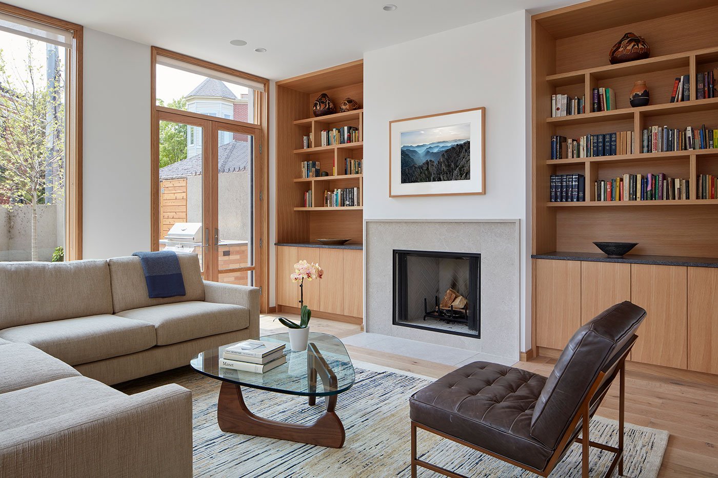 A study with a fireplace and built-in shelves is well connected to the outdoors through the floor-to-ceiling E-Series Windows and E-Series Hinged Patio Door with transom.