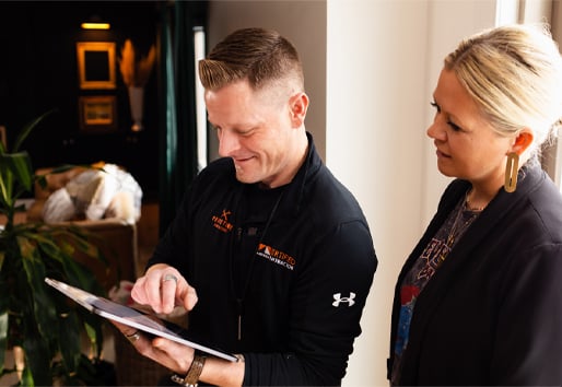 A contractor shows a homeowner something on his tablet.