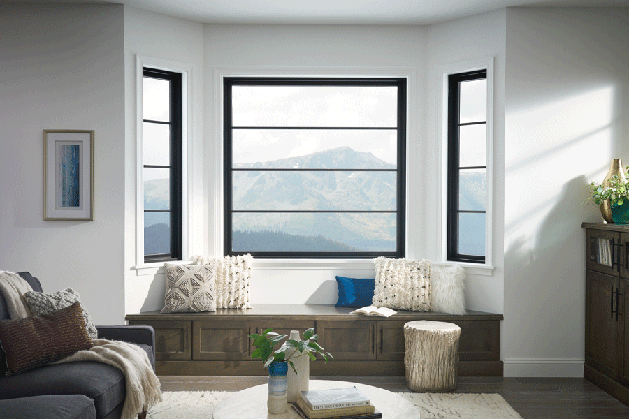 Three modern black-framed living room windows frame mountain views.