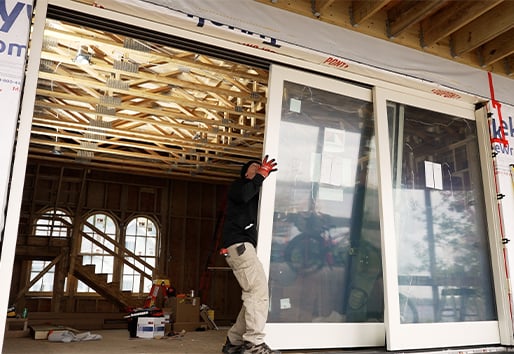 A man installs a MultiGlide door panel into a rough opening.
