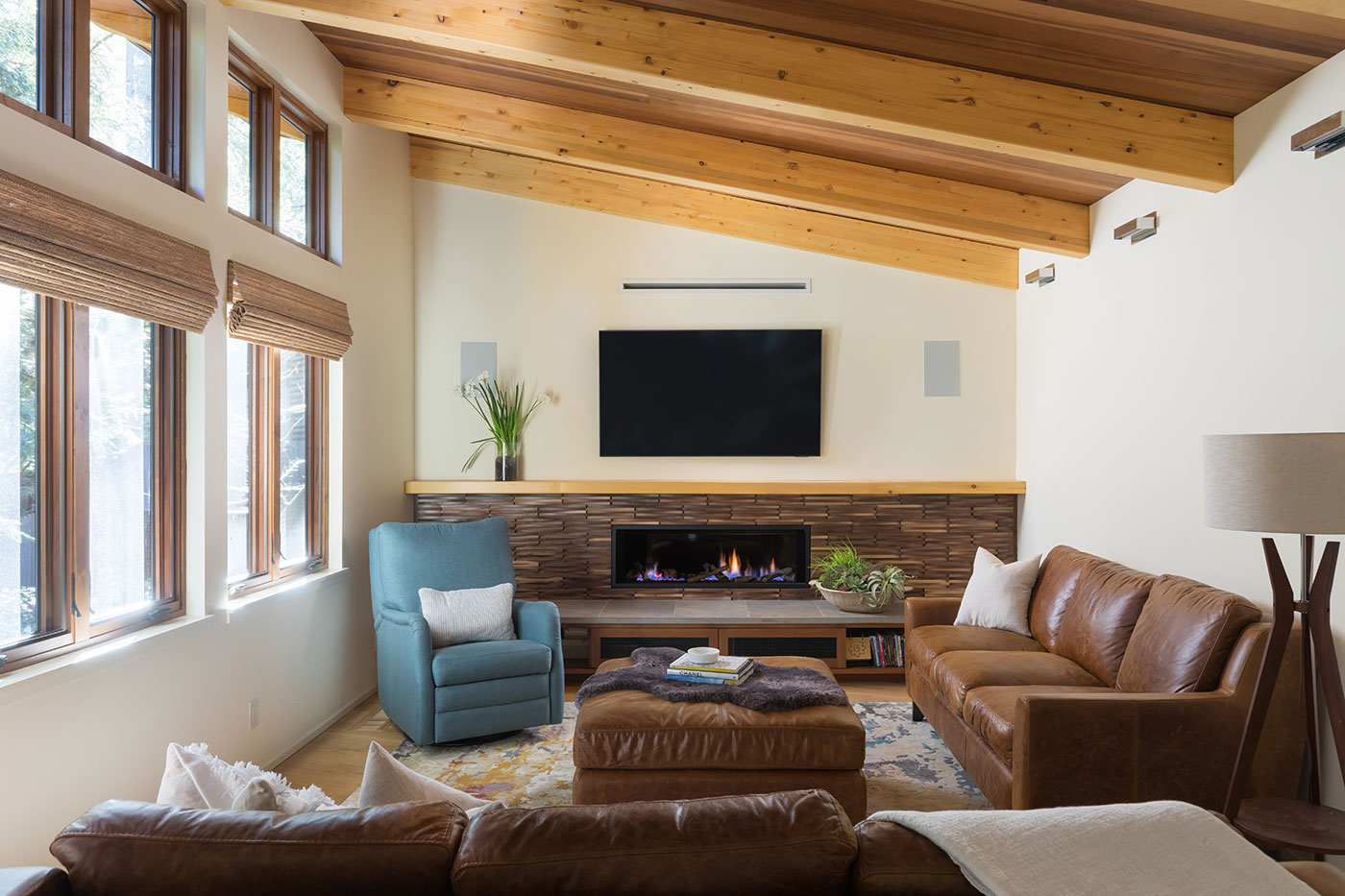 A cozy living room with fireplace, two rows of windows, and a wooden ceiling.