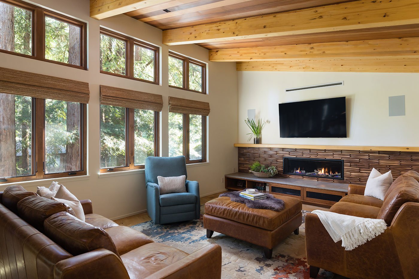 A view of a living room with comfy leather furnishings and large wood windows.