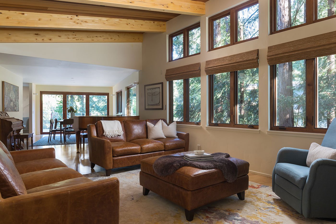 A living room and dining room beyond with windows and doors on three walls.