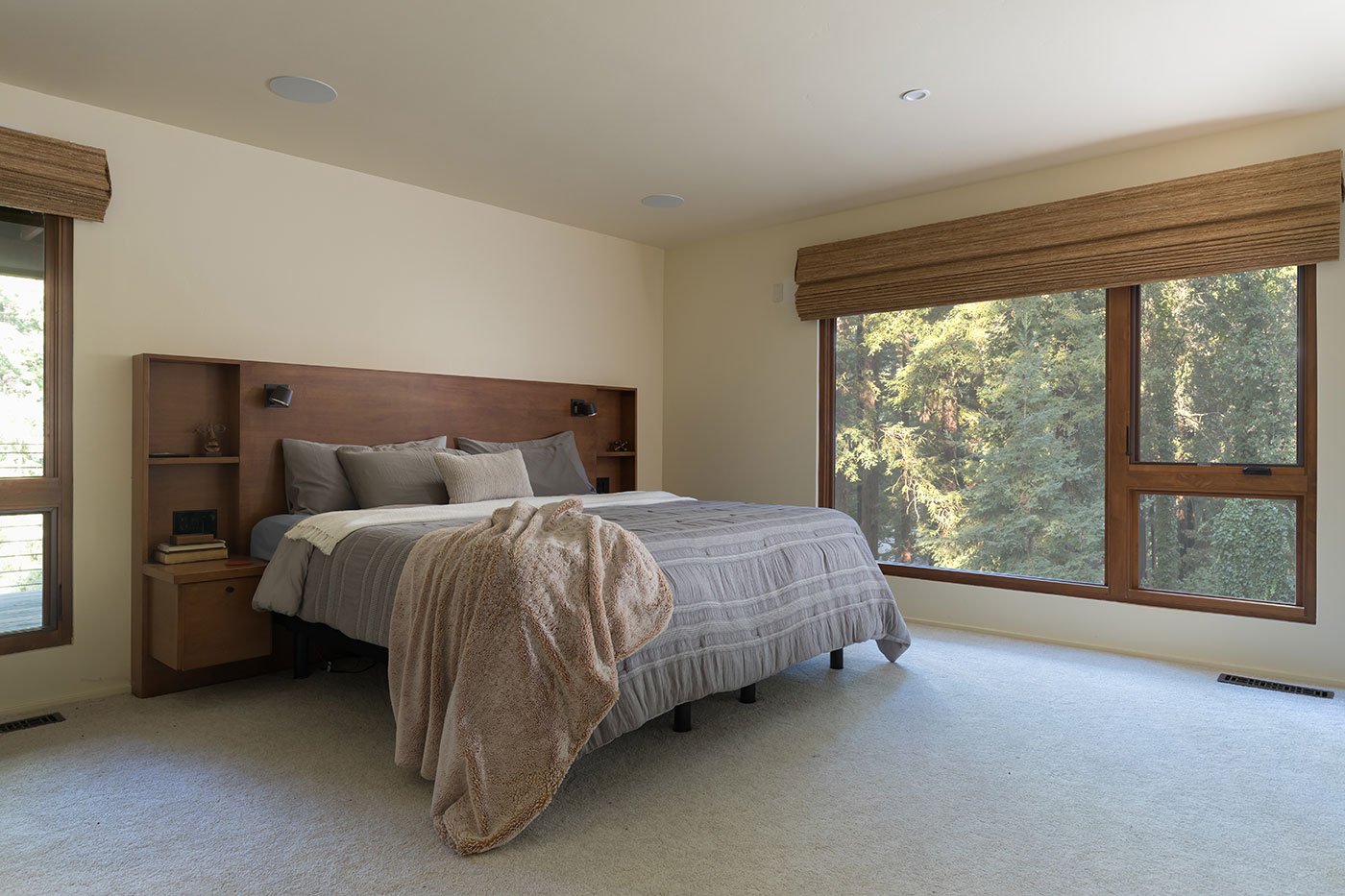 A bedroom with large combinations of mulled windows on two walls.