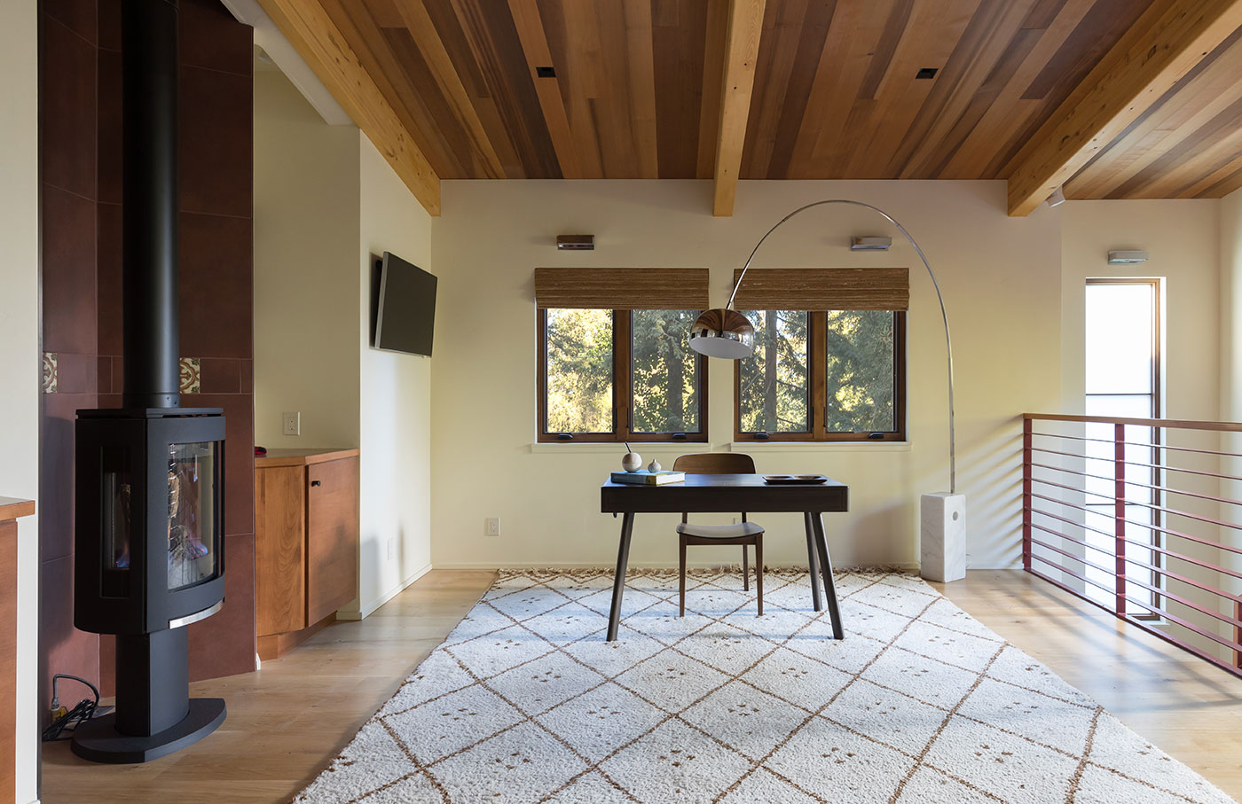 an office with a wood burning stove, desk, and arched light over a desk.