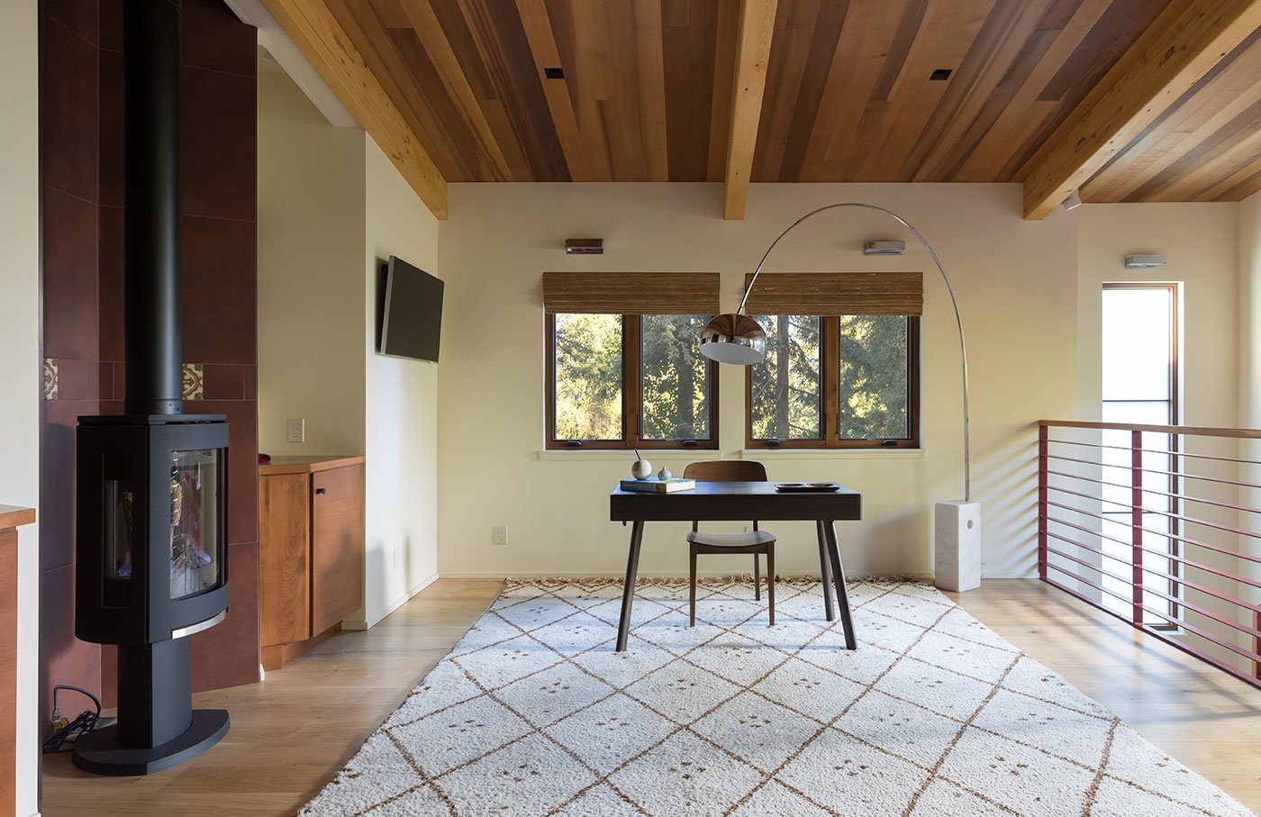 an office with a wood burning stove, desk, and arched light over a desk.