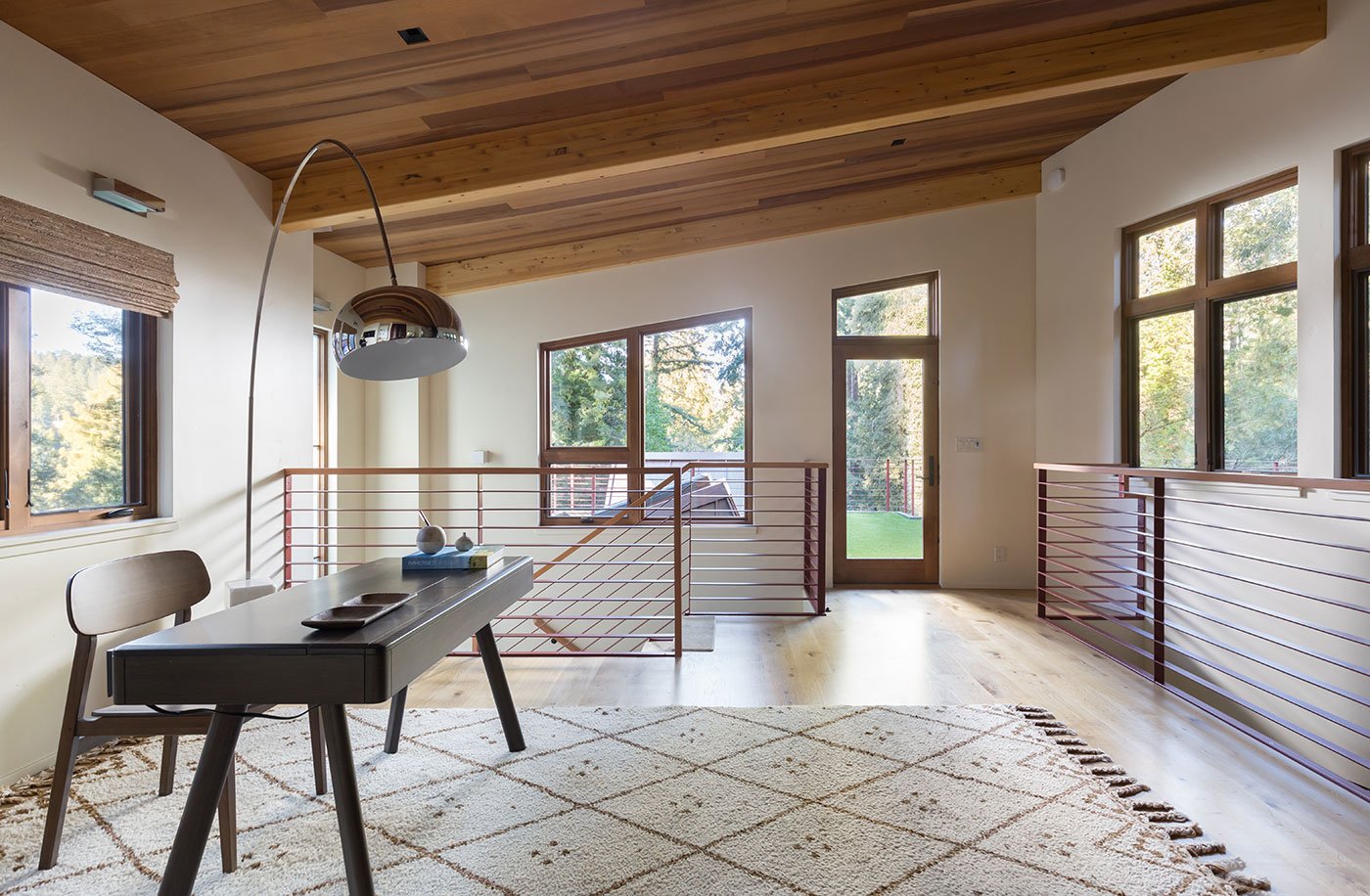An office space with windows on three walls and a wood ceiling.