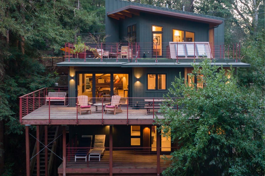 A contemporary home with three levels of decks blends into the thick tree canopy surrounding it. 