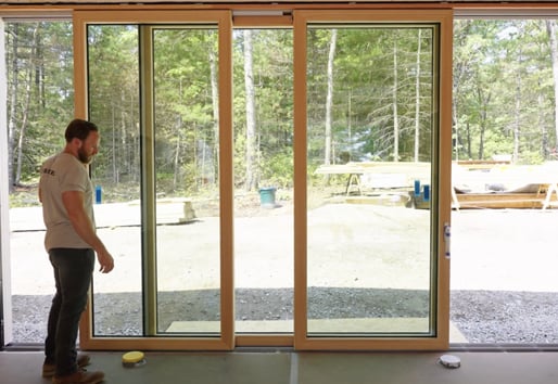Schiffer demonstrates how the operable side panels on the woods-facing Liftslide Door meet in the middle of the large, fixed center panel.