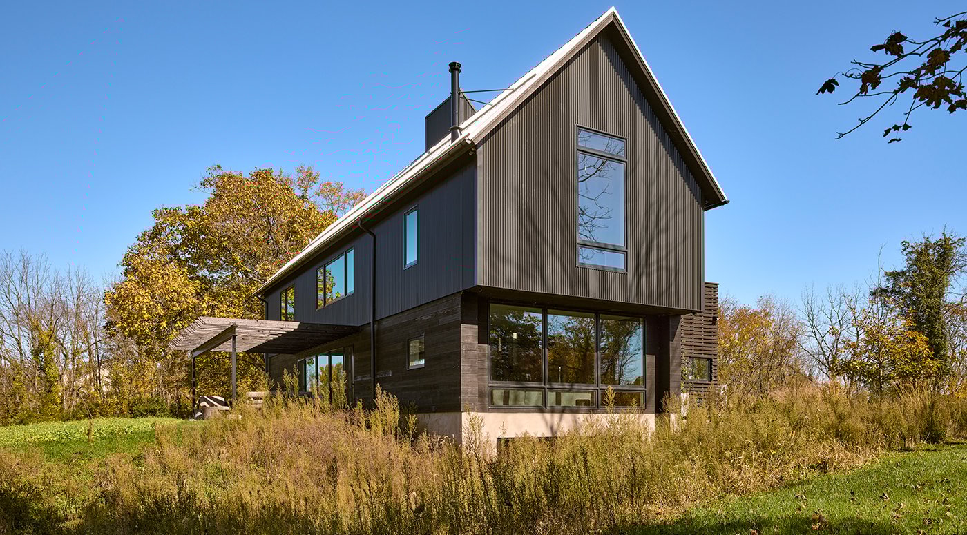 A barn-style home with black metal cladding and massive windows.