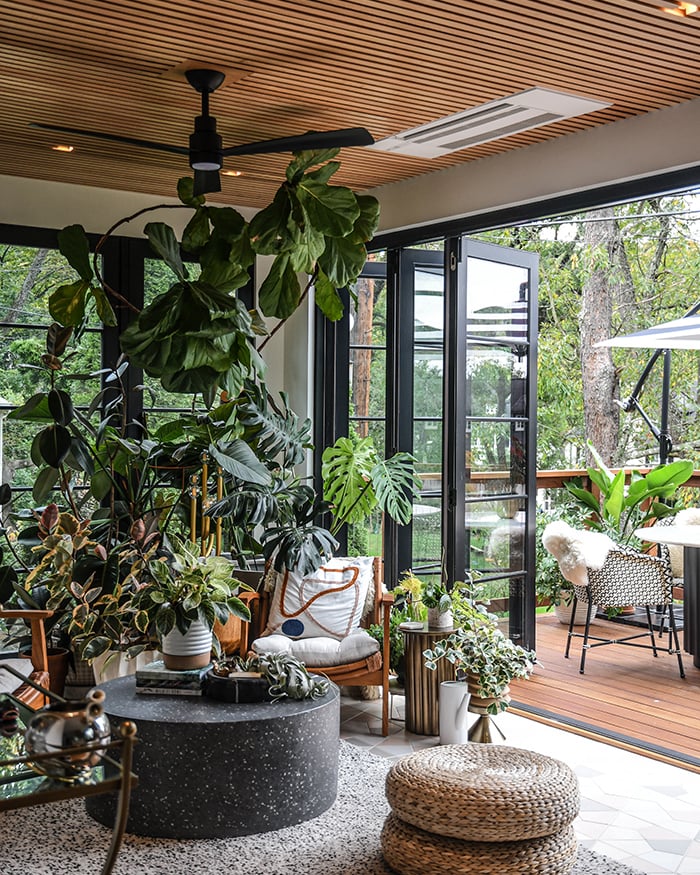 A before-and-after home remodel showing a wall replaced with black-framed glass doors to create more light, openness, and indoor/outdoor connection. 