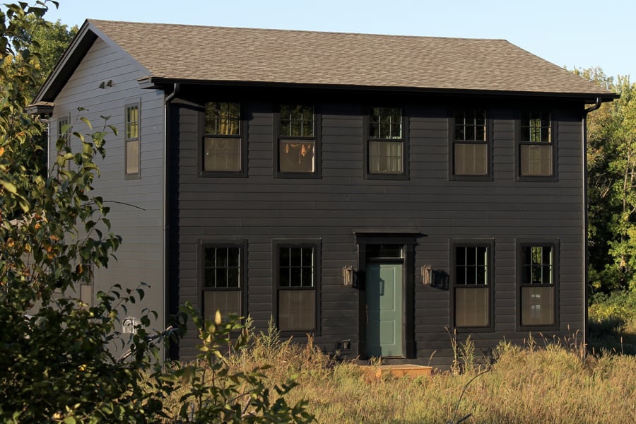 A black house with black windows standing in a field.