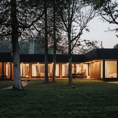 A modern style home sits at dusk with large black windows.