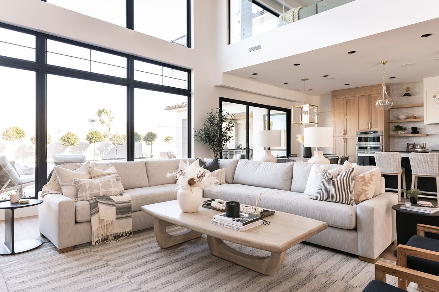 An interior image of a neutral-color-themed living room with a black Multi-Slide Door, and 100 Series Picture with transoms.