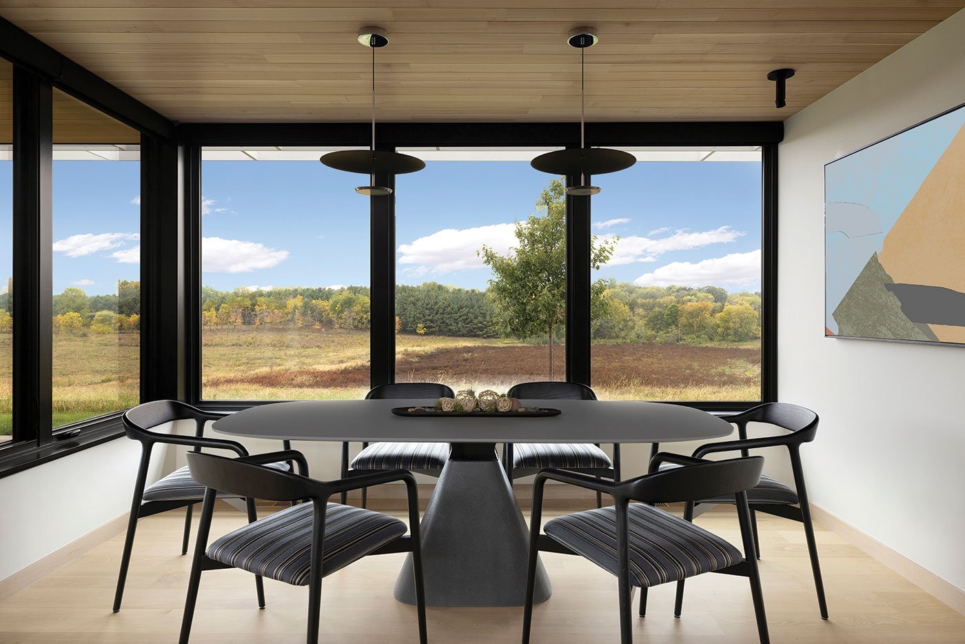 A dining nook with black-framed casement windows taking up two walls.
