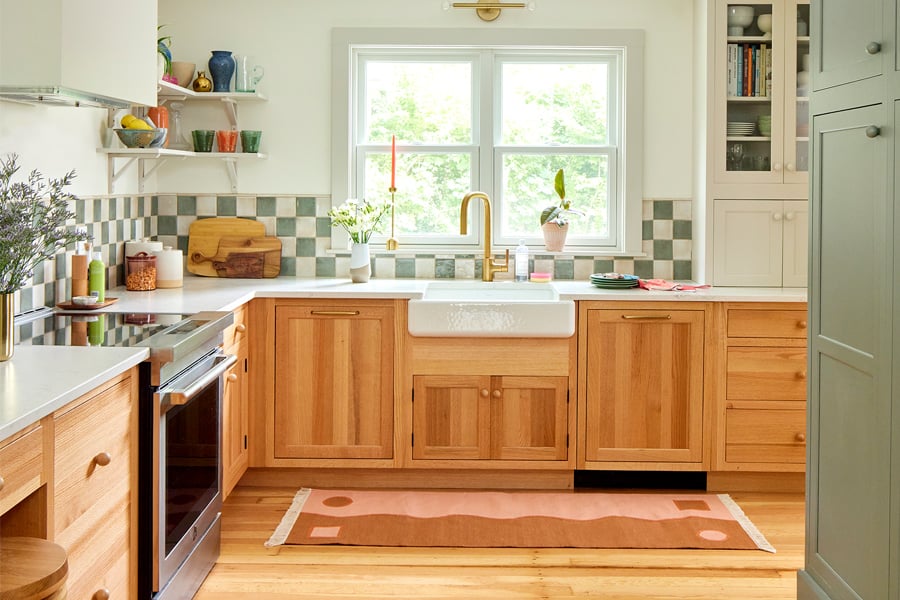 A bright kitchen with white walls, 200 Series double-hung windows, wood cabinets, and green accents.