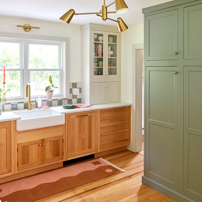 kitchen with green, white and wooden cabinets, a white farm sink, and checkered green and white backsplash