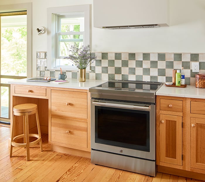 kitchen with hardwood floors and wood cabinets, an oven and desk seating area with a stool and double-hung window.
