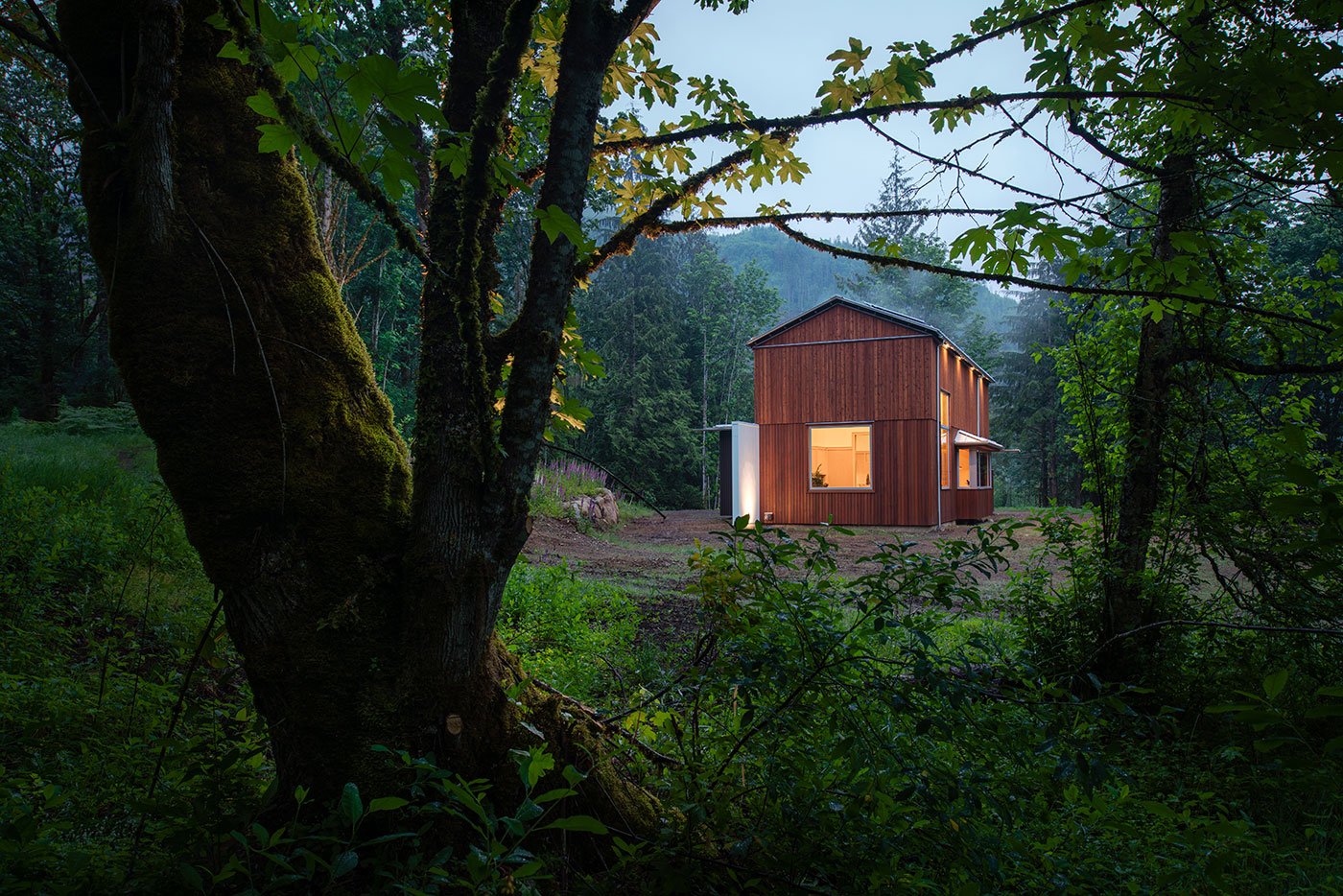 An exterior shot of a barn-shaped home with vertical cedar cladding and large windows.