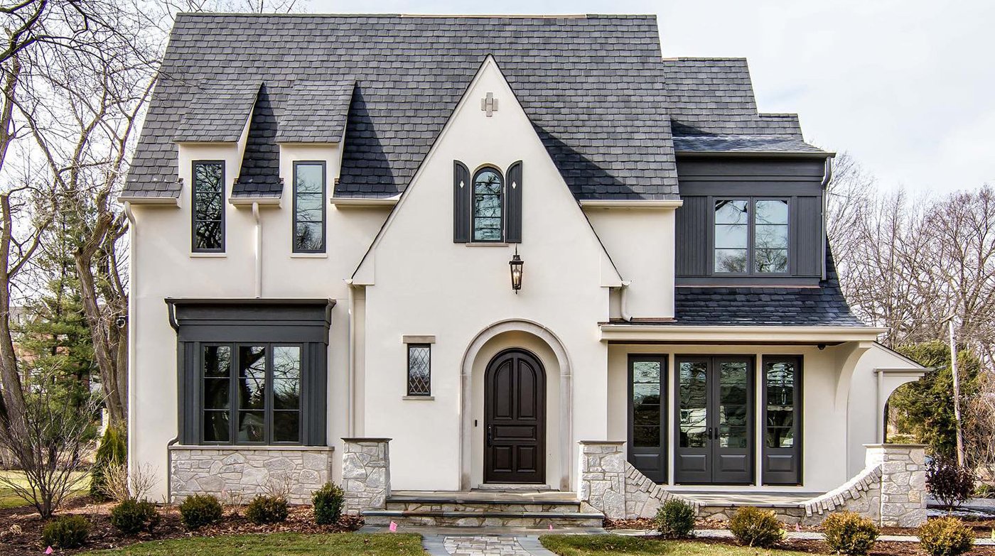 A Modern Tudor home made of white stucco with black windows, doors, and other archictural accents.