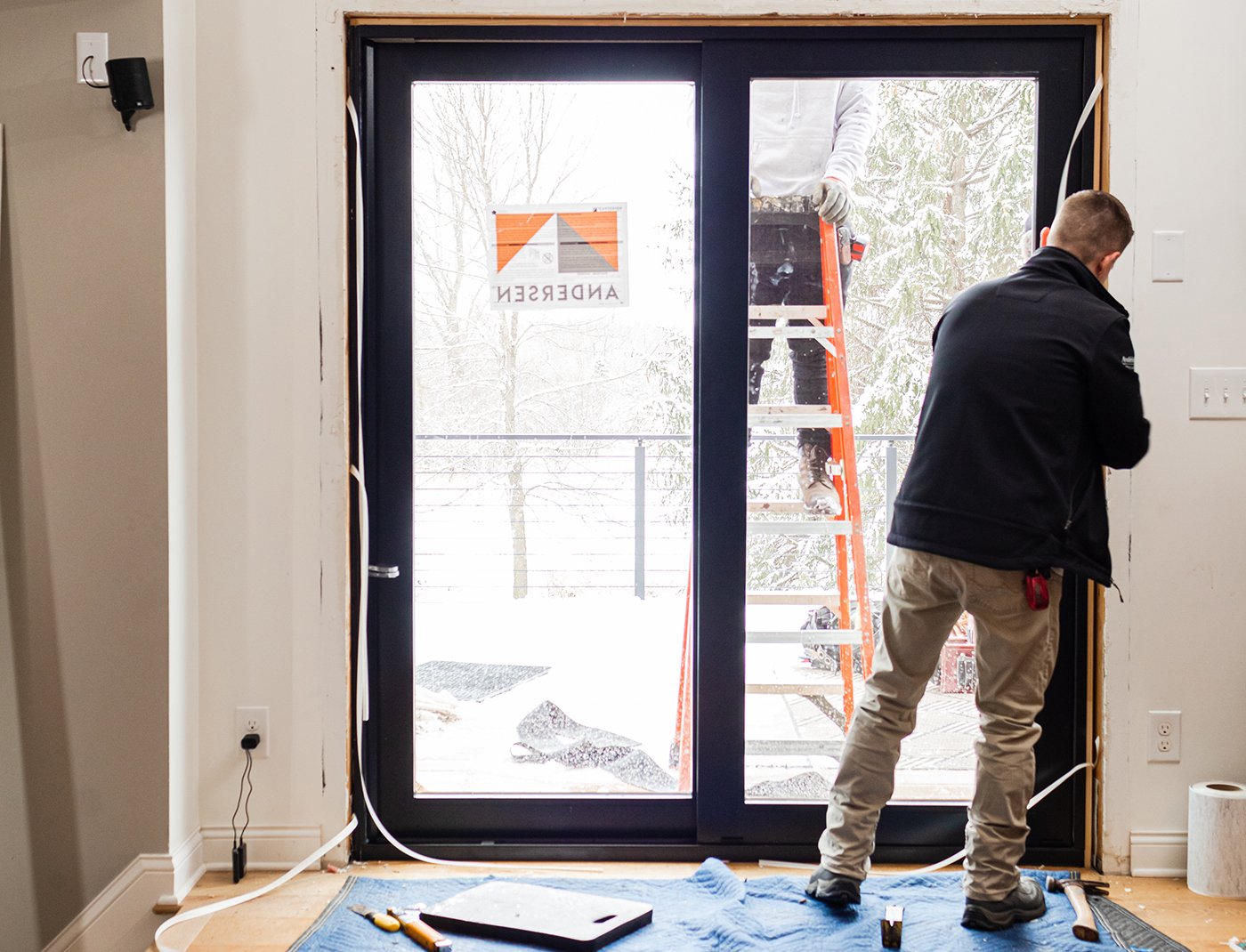 Two men installing a new patio door in a kitchen.