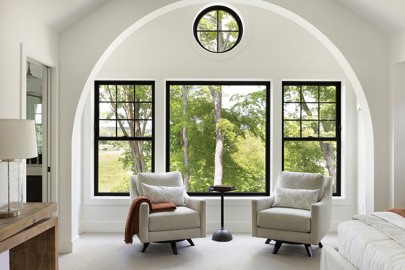 A bedroom with an Andersen® 100 Series Picture Window flanked by two 100 Series Single-Hung Windows.
