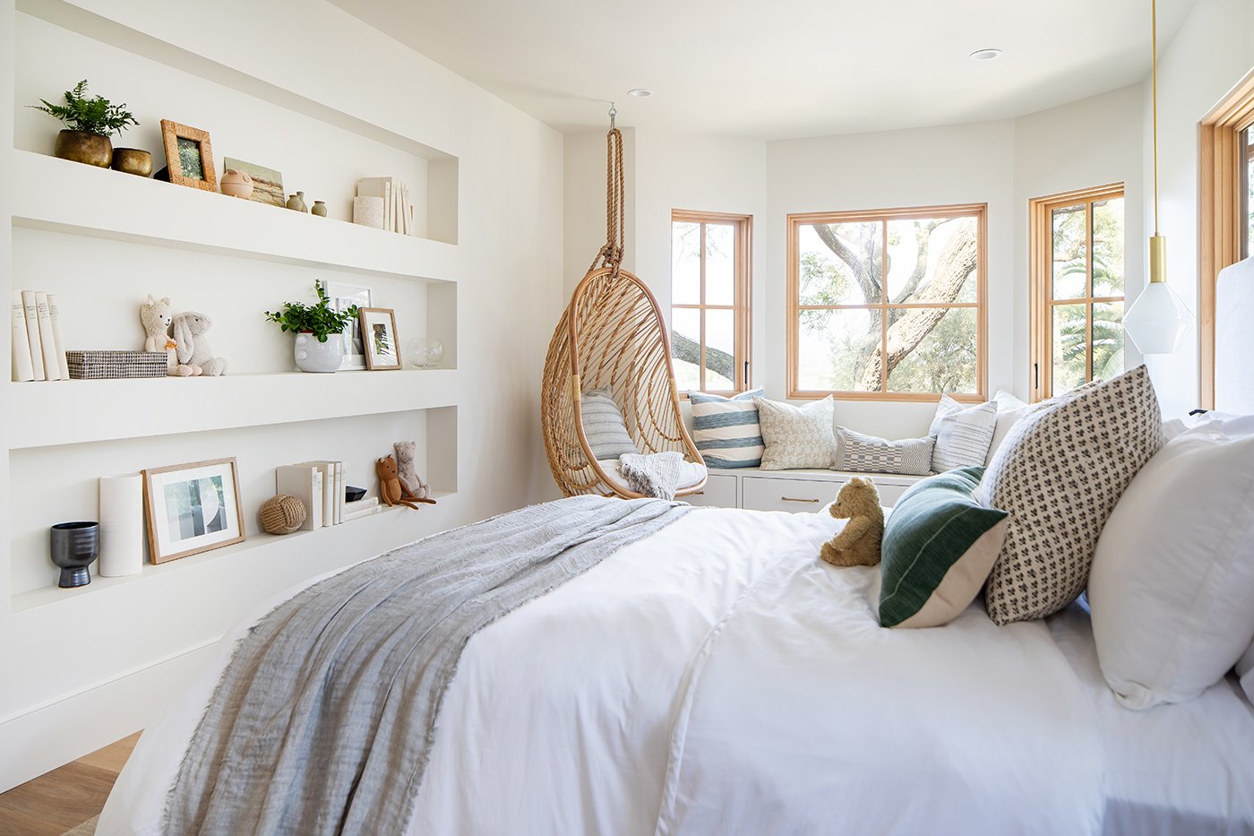 A child’s bedroom with a walk-out bay featuring Andersen® E-Series windows with white oak frames