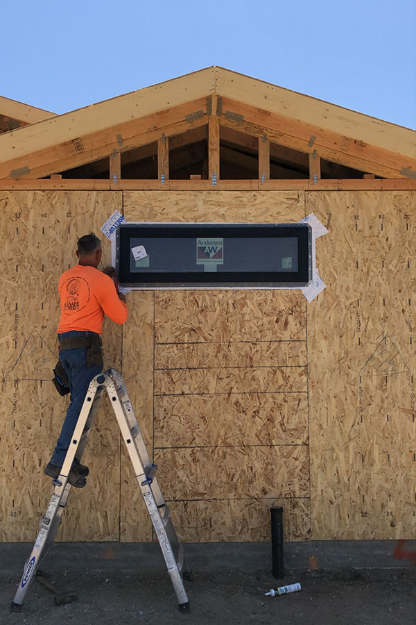 construction guy working on installing Andersen window on new construction