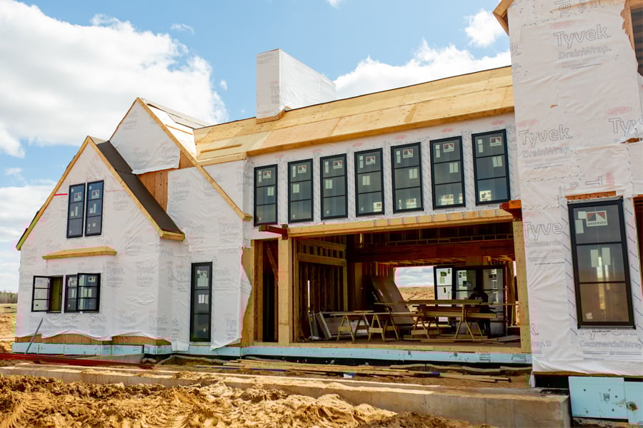 An under-construction home with windows and house wrap installed.