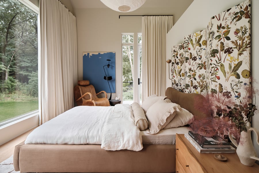 A bedroom with a large picture window at the end of the bed and a hinged door with sidelights and transoms leading out to a deck.