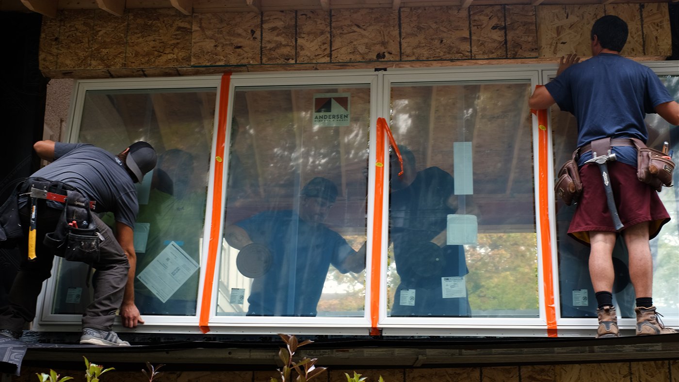 Four men installing a joined window unit made of four 400 Series Casement Windows.