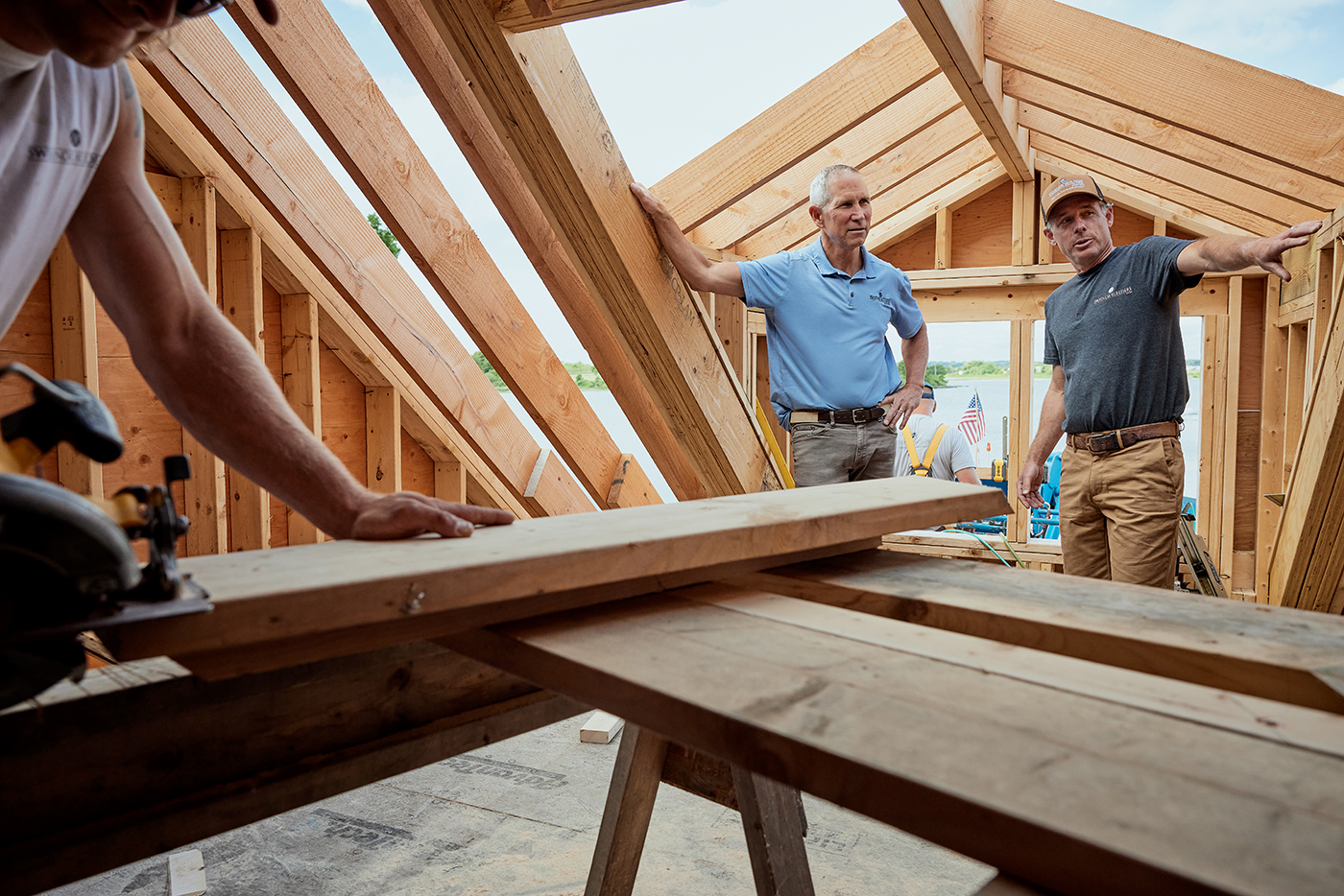Men stand in the attic of a new-construction home that’s in the process of being framed.