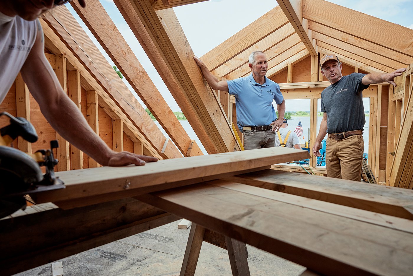 Men stand in the attic of a new-construction home that’s in the process of being framed.