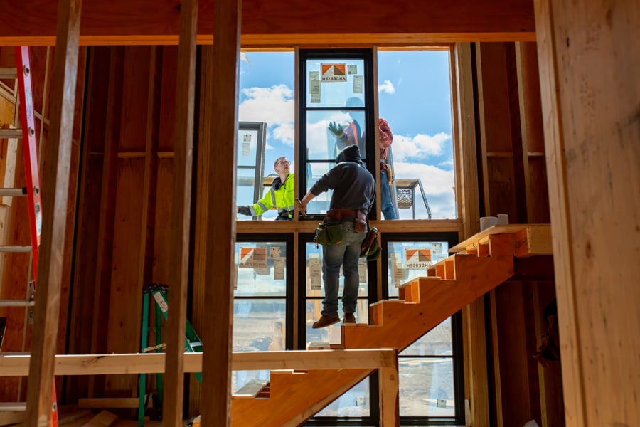 Men installing a wall of windows next to a stair.