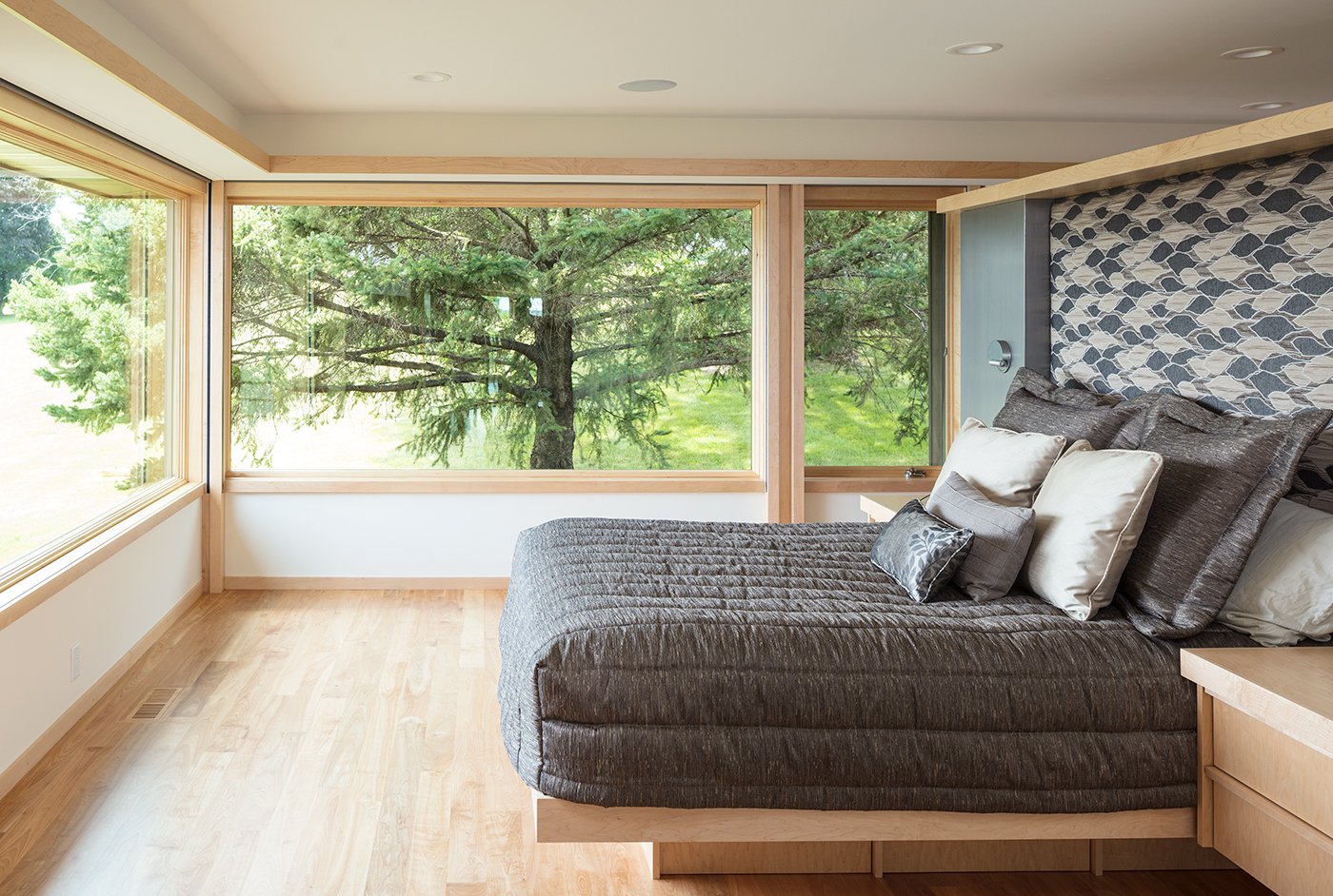 A wide-open bedroom with large A-Series Casement and Picture Windows with light frames that match the hardwood floors.