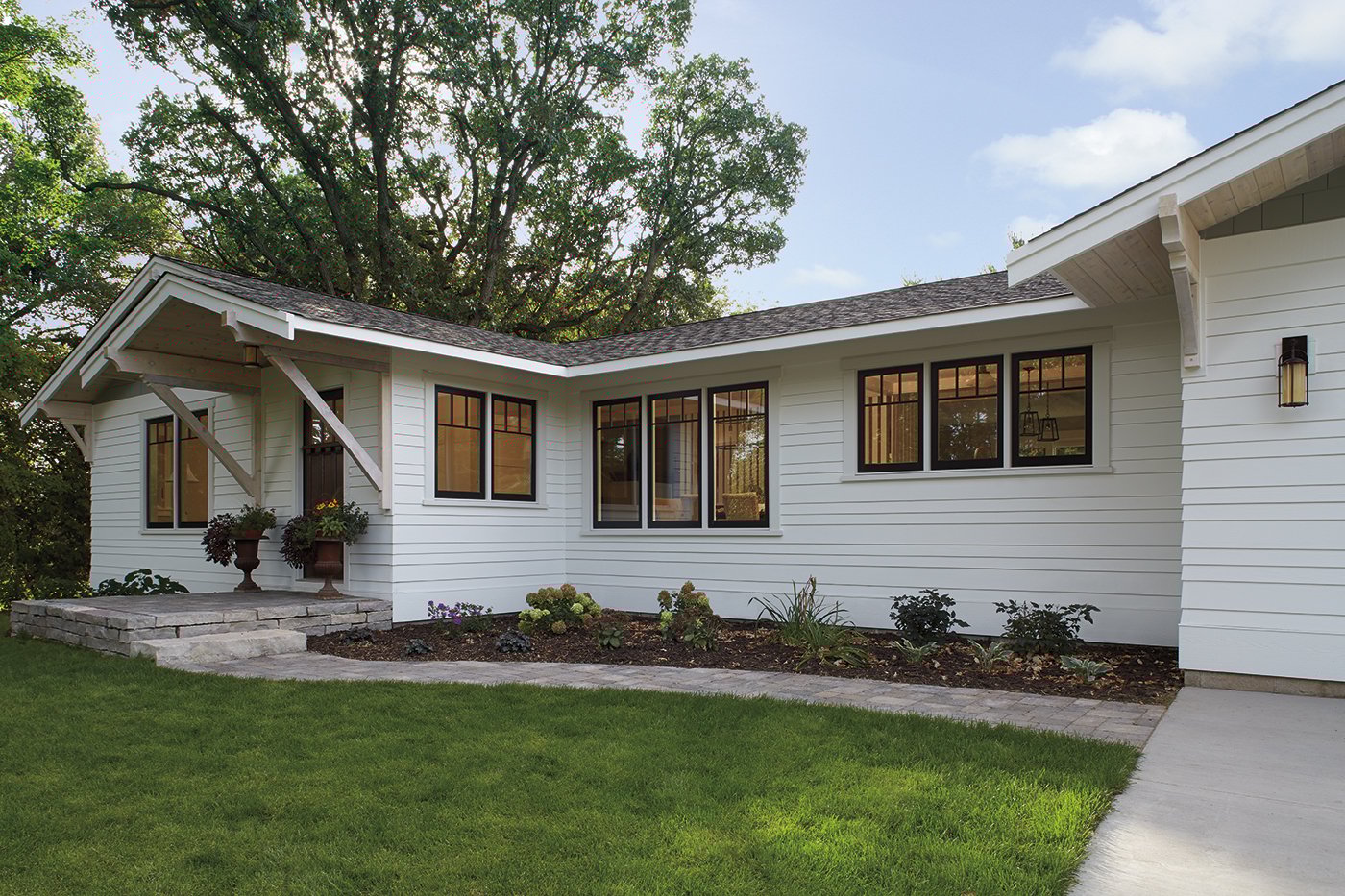 The exterior of a white single floor home with casement windows with dark frames.