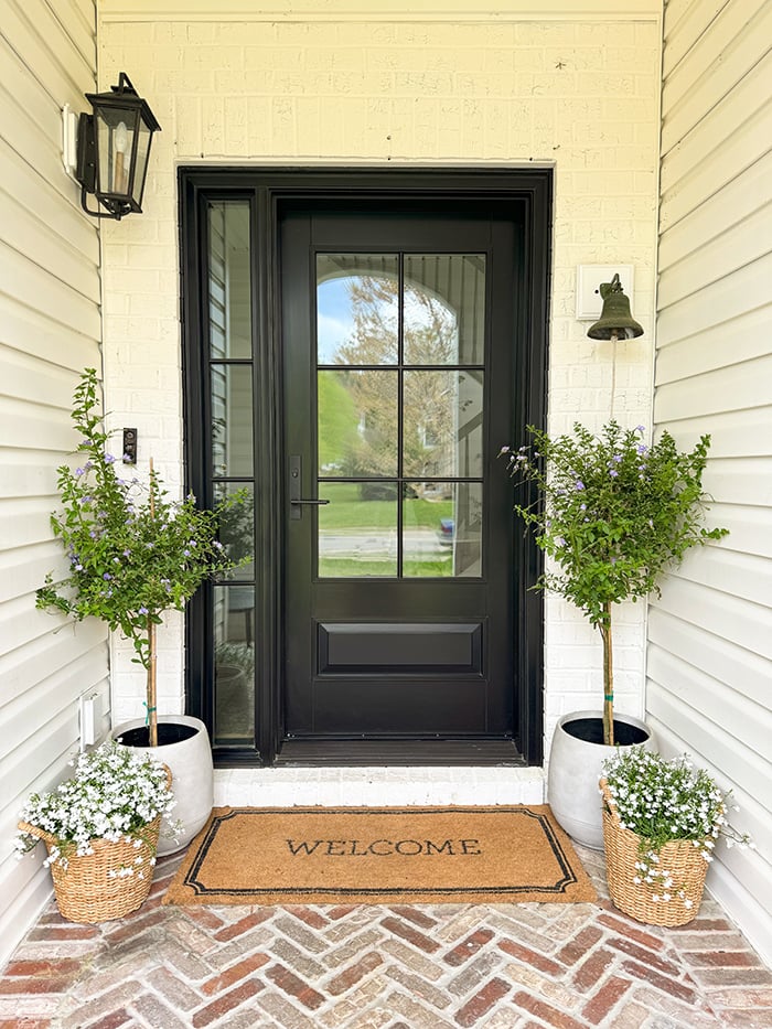 An exterior view of a black front door after a front door replacement on the right and an exterior view of the old door on the left. 